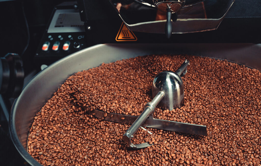 Small-batch roasting machine filled with freshly roasted coffee beans, illustrating Ricco Coffee’s artisan approach to craft roasting and quality control