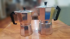 A pair of Moka Pots in large and medium sizes displayed on a wooden surface, encapsulating the essence of Moka Pot coffee brewing as explored in the guide's conclusion.
